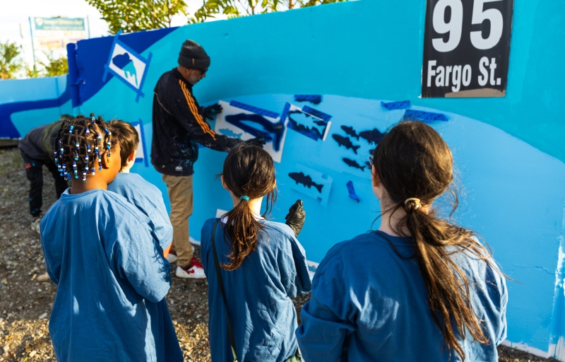 Felipe Ortiz shows Members of the South Boston Boys and Girls Club how to spray paint the mural
