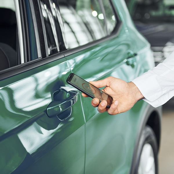 Man holding phone up to rental car to unlock