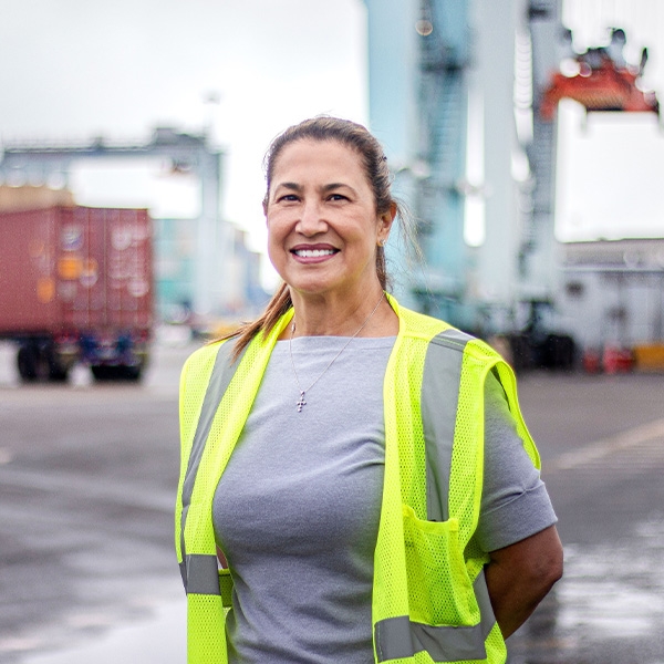 Person smiling, standing in a cargo terminal