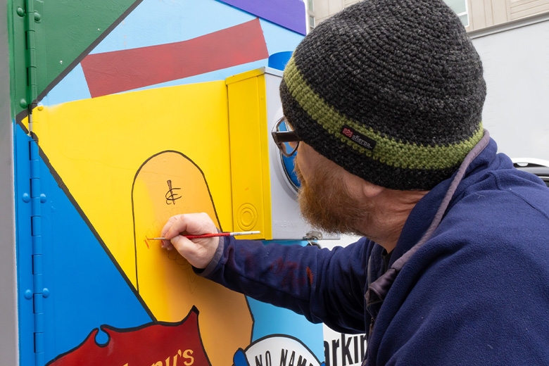 Artist painting on utility box