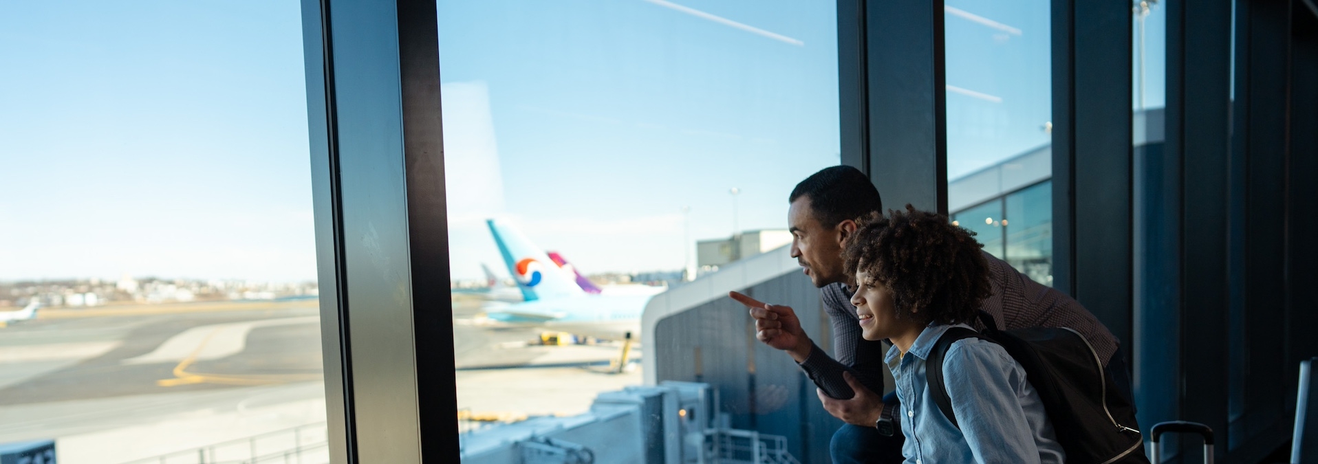 Father and son on winter break looking out airport window