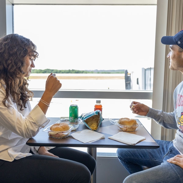 Two people sitting eating food at the airport