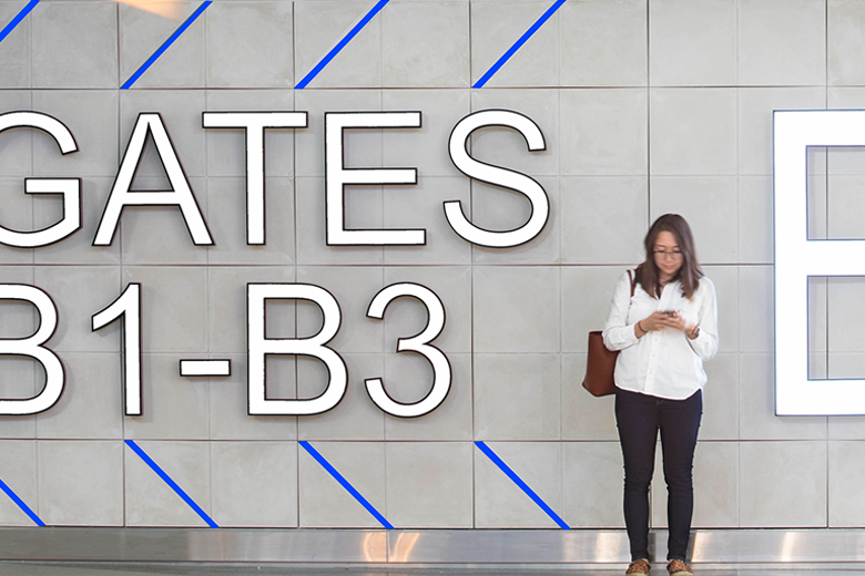 Woman looking at her cell phone in Terminal B at Boston Logan