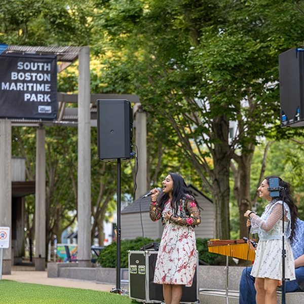 Two women singing in the South Boston Maritime Park