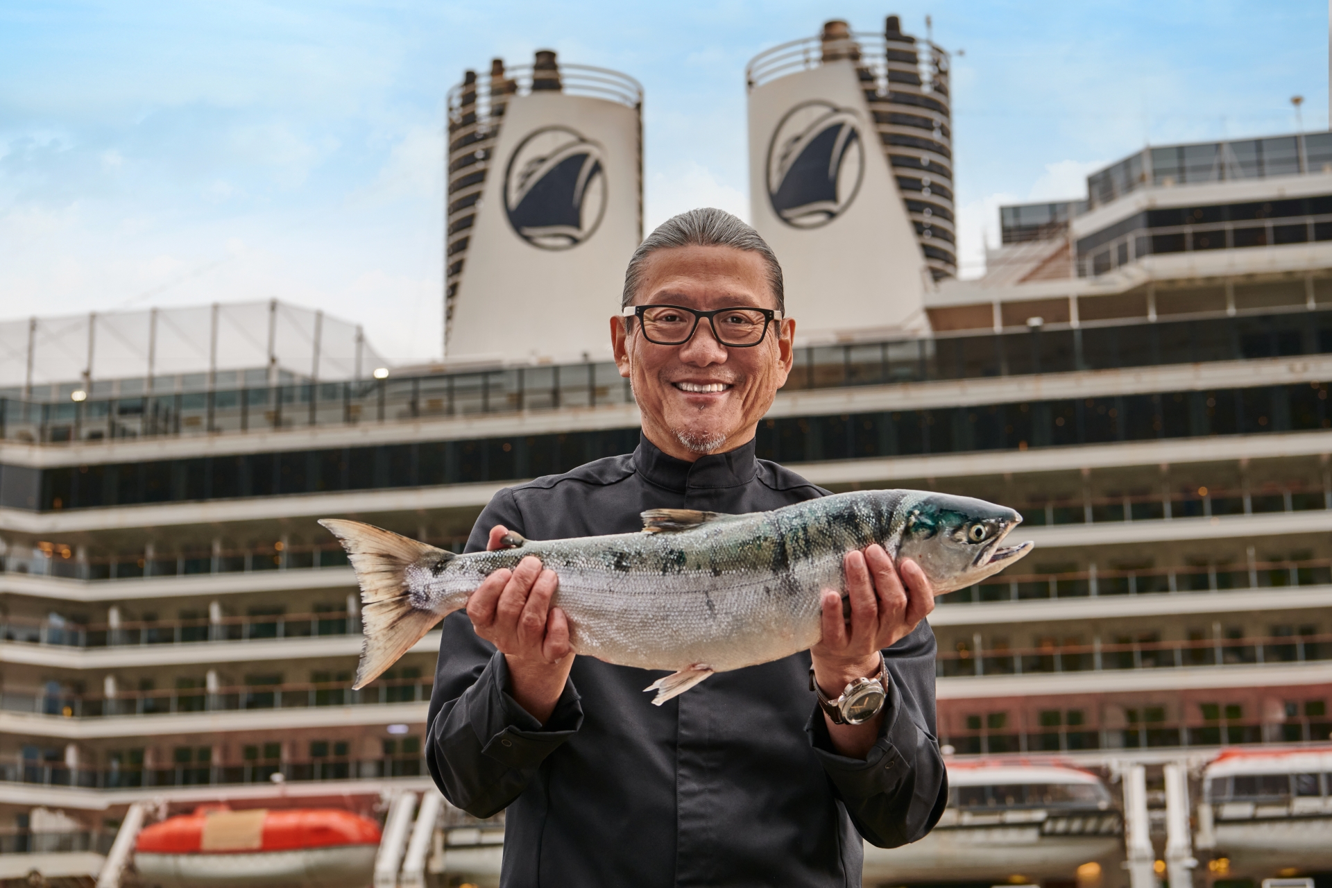 Man holding fish in front of Holland America Cruise ship