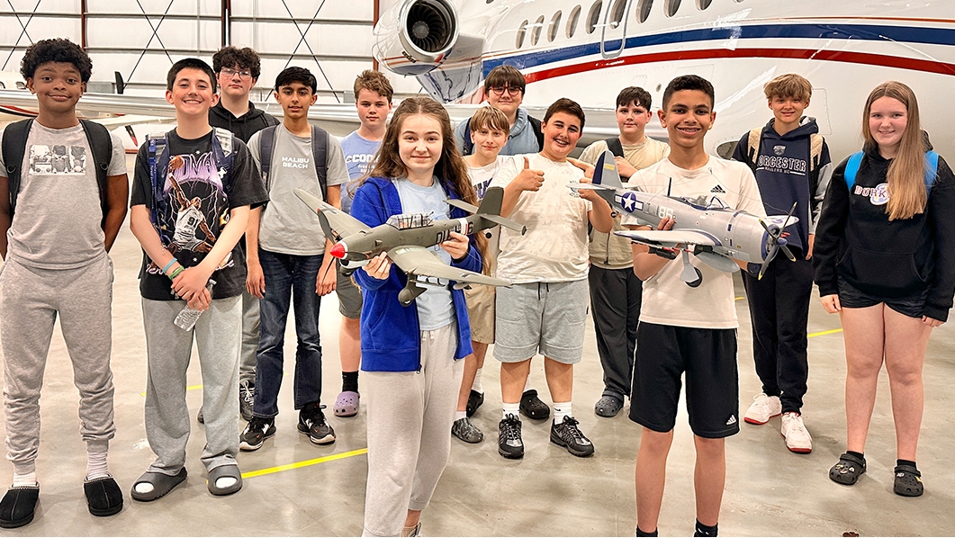 Students standing in front of plane in hanger