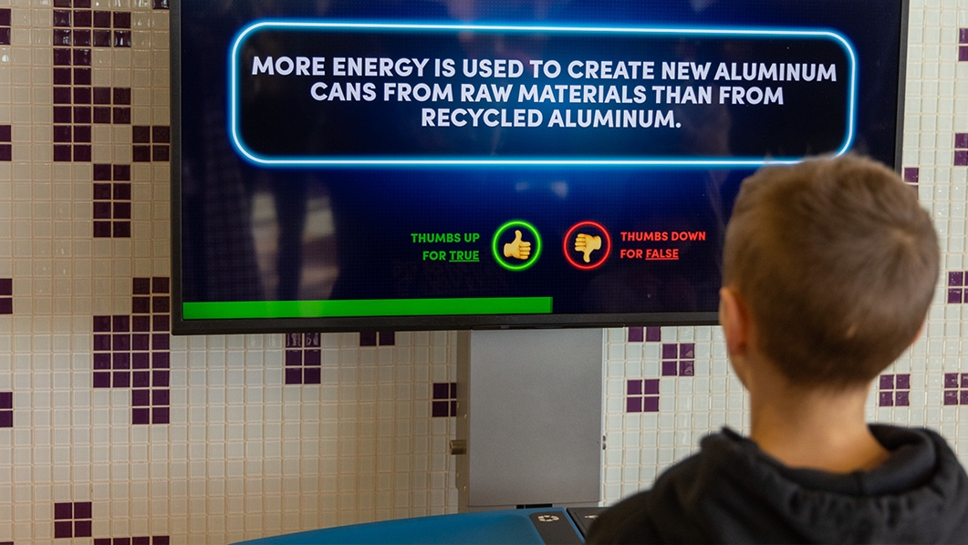 Boy using Oscar Recycling machine at Boston Logan