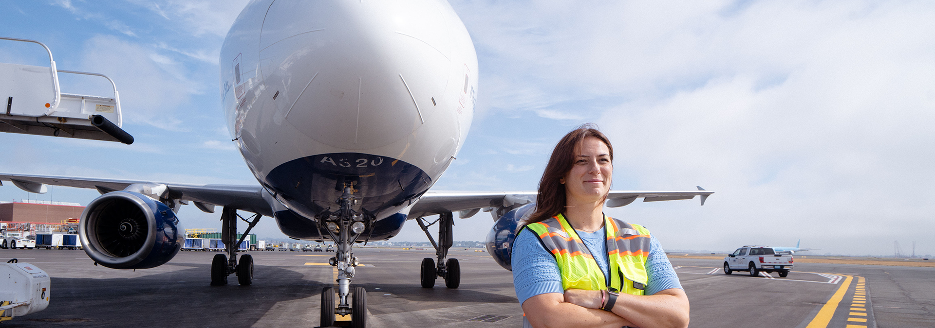 Woman on the airfield in hi vis vest in front of an airplane