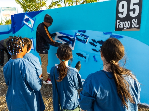 Felipe Ortiz shows Members of the South Boston Boys and Girls Club how to spray paint the mural
