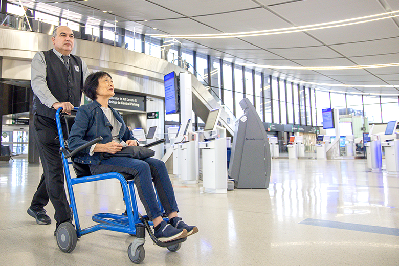 man pushing women in a wheelchair through terminal
